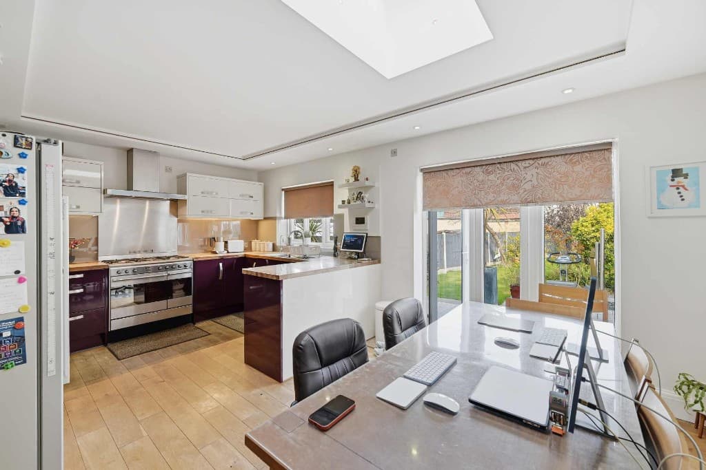 Open-plan kitchen diner with laptops, clutter and fridge magnets before cleanup
