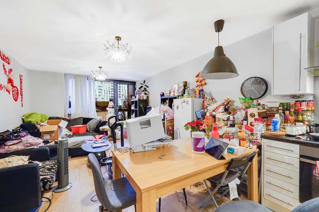 Cluttered open-plan living and dining room before AI photo cleanup